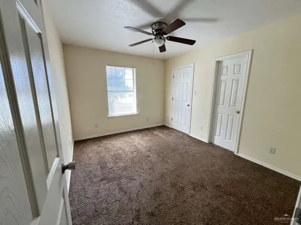 an empty room with windows and fan