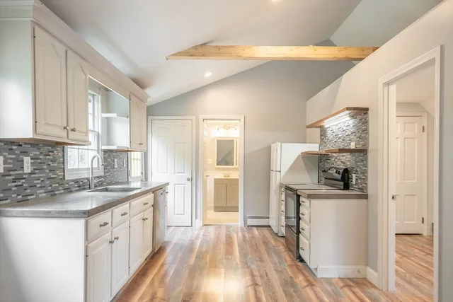 a kitchen with stainless steel appliances granite countertop a refrigerator a sink dishwasher a stove and white countertops with wooden floor