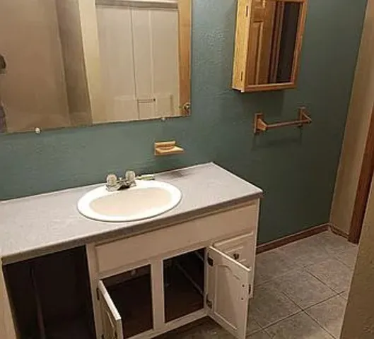 a sink sitting under a bathroom mirror