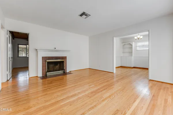 a view of empty room with wooden floor and fireplace