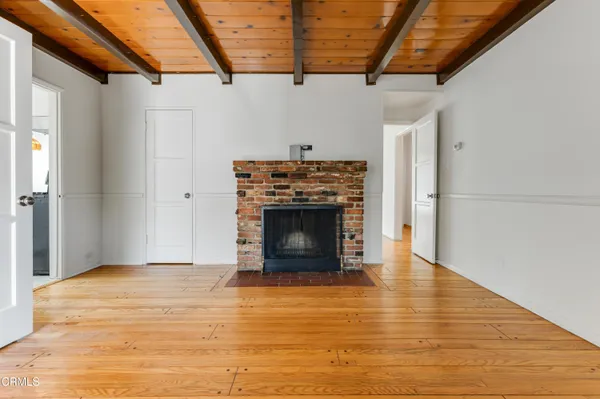 a view of an empty room with wooden floor fireplace and a window