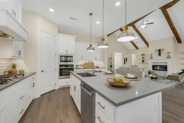 a kitchen with a sink dishwasher a stove and white cabinets with wooden floor