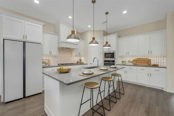 a open kitchen with stainless steel appliances granite countertop a stove a sink a kitchen island and chairs with wooden floor