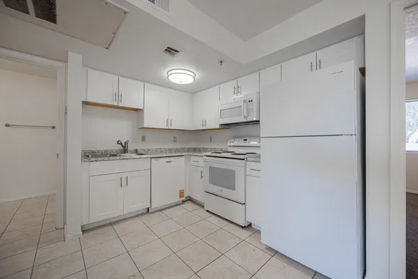 a kitchen with white cabinets and white appliances