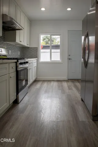 a kitchen with granite countertop wooden floors stainless steel appliances and window