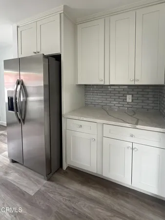 a kitchen with a refrigerator and white cabinets