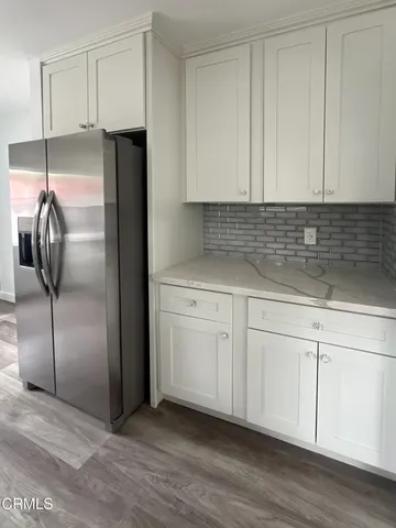 a kitchen with a refrigerator and white cabinets