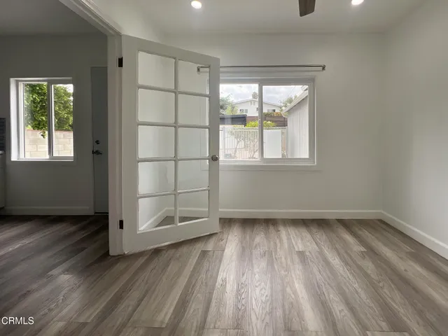 an empty room with wooden floor and windows
