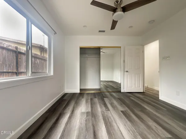 a view of an empty room with wooden floor and a window