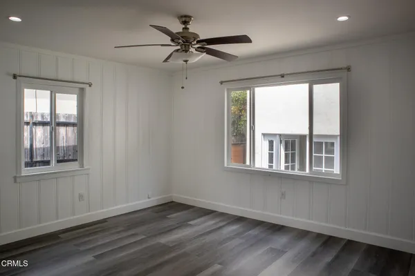 an empty room with wooden floor and windows