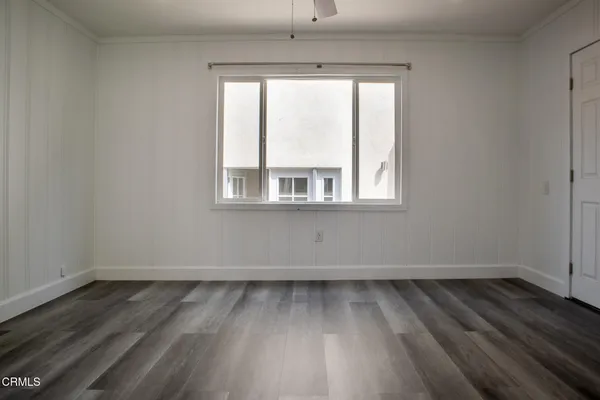 a view of an empty room with wooden floor and a window