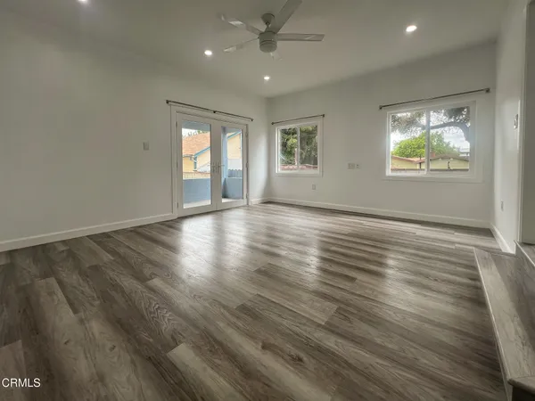an empty room with wooden floor and windows