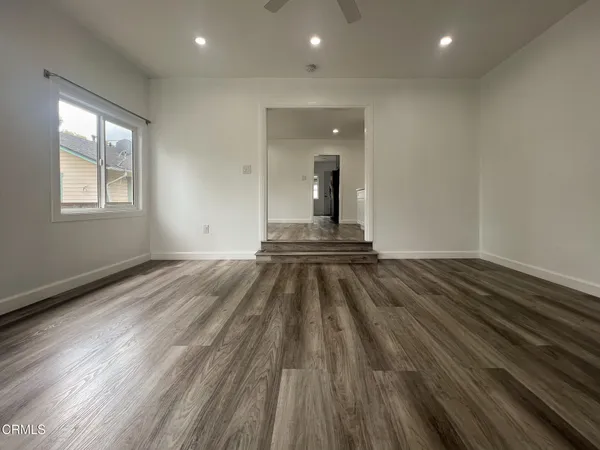 a view of empty room with wooden floor and fan