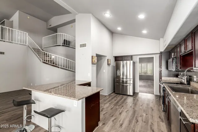 a kitchen with stainless steel appliances granite countertop a refrigerator a stove a sink dishwasher a dining table and chairs with wooden floor