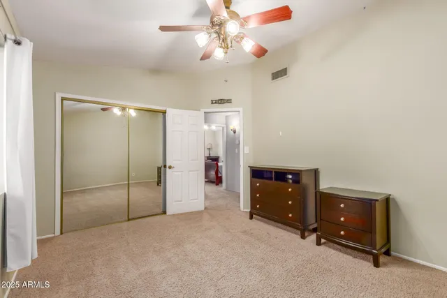 an empty room with closet and a chandelier fan