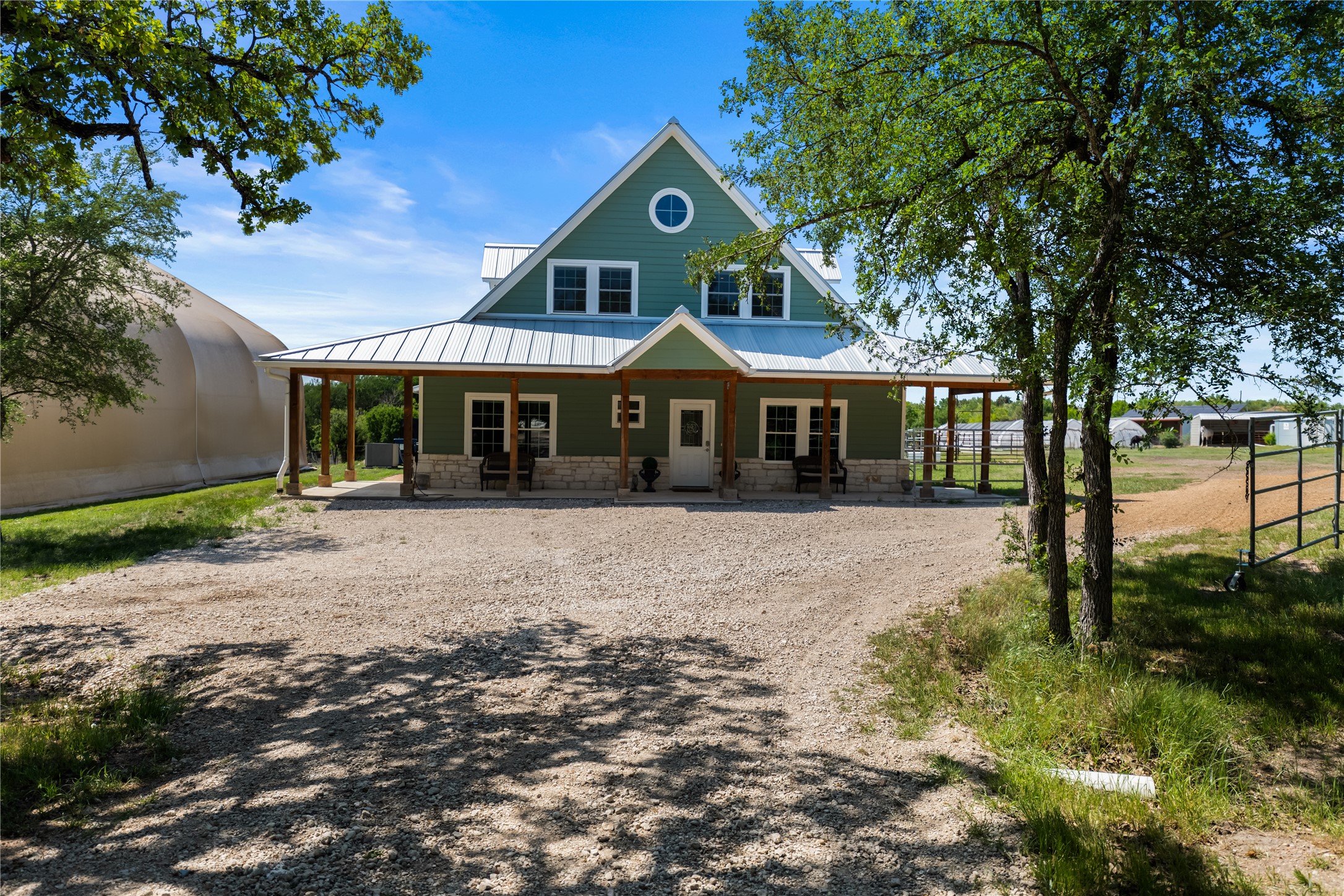 7670 Nez Perce Trace Manor, TX 78653 - Photo 20 of 40 Country-style home with driveway, stone siding, a porch, a standing seam roof, and metal roof