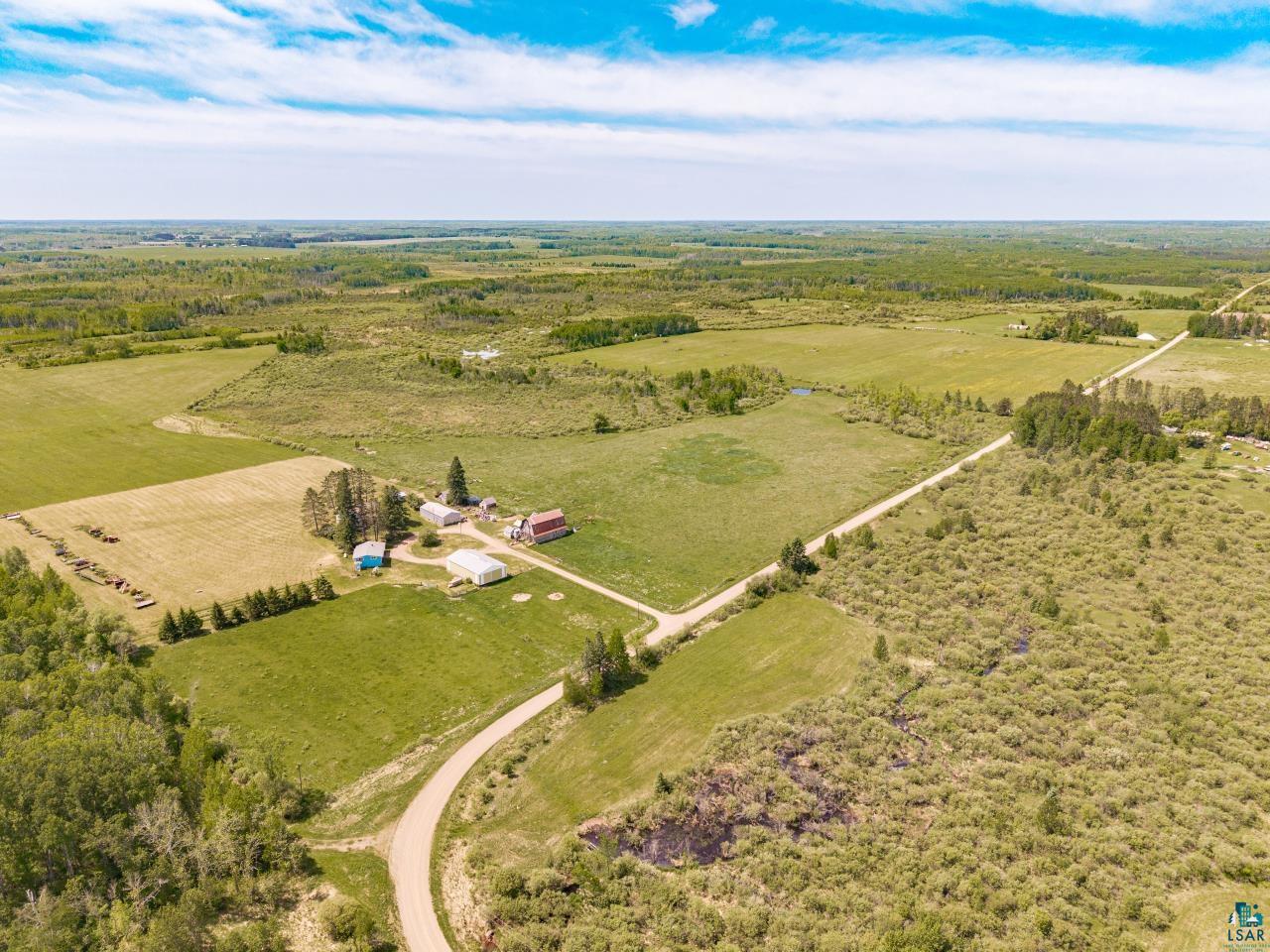 6606 Metso Road Kettle River, MN 55757 - Photo 5 of 84 Expansive rural property featuring multiple structures, cultivated fields, unpaved roads, and dense tree lines