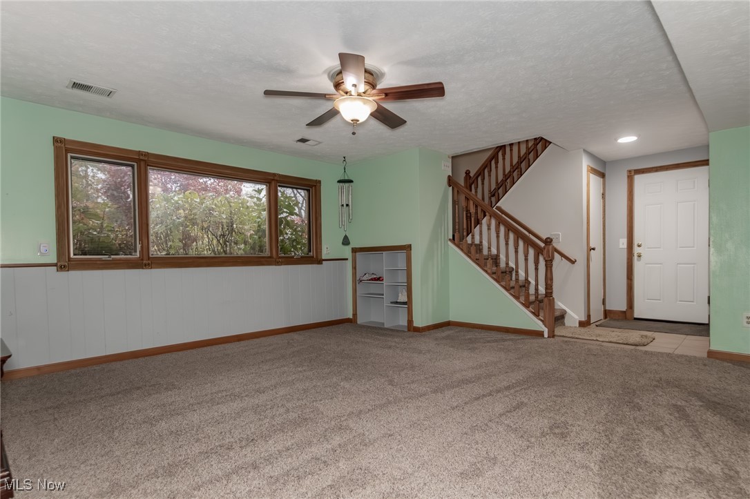 12745 Carter Road Painesville, OH 44077 - Photo 8 of 50 Unfurnished living room with stairs, light carpet, a textured ceiling, and ceiling fan