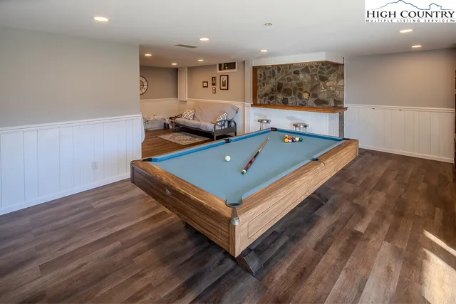 a room with wooden floor pool table furniture and windows