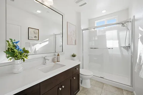 a bathroom with a shower sink vanity mirror and toilet