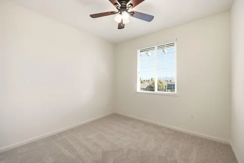 an empty room with a window and a fan