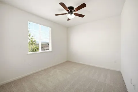 an empty room with a window and a fan