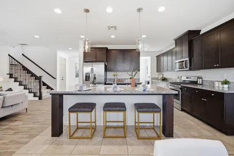 a kitchen with stainless steel appliances granite countertop a table chairs sink refrigerator and microwave