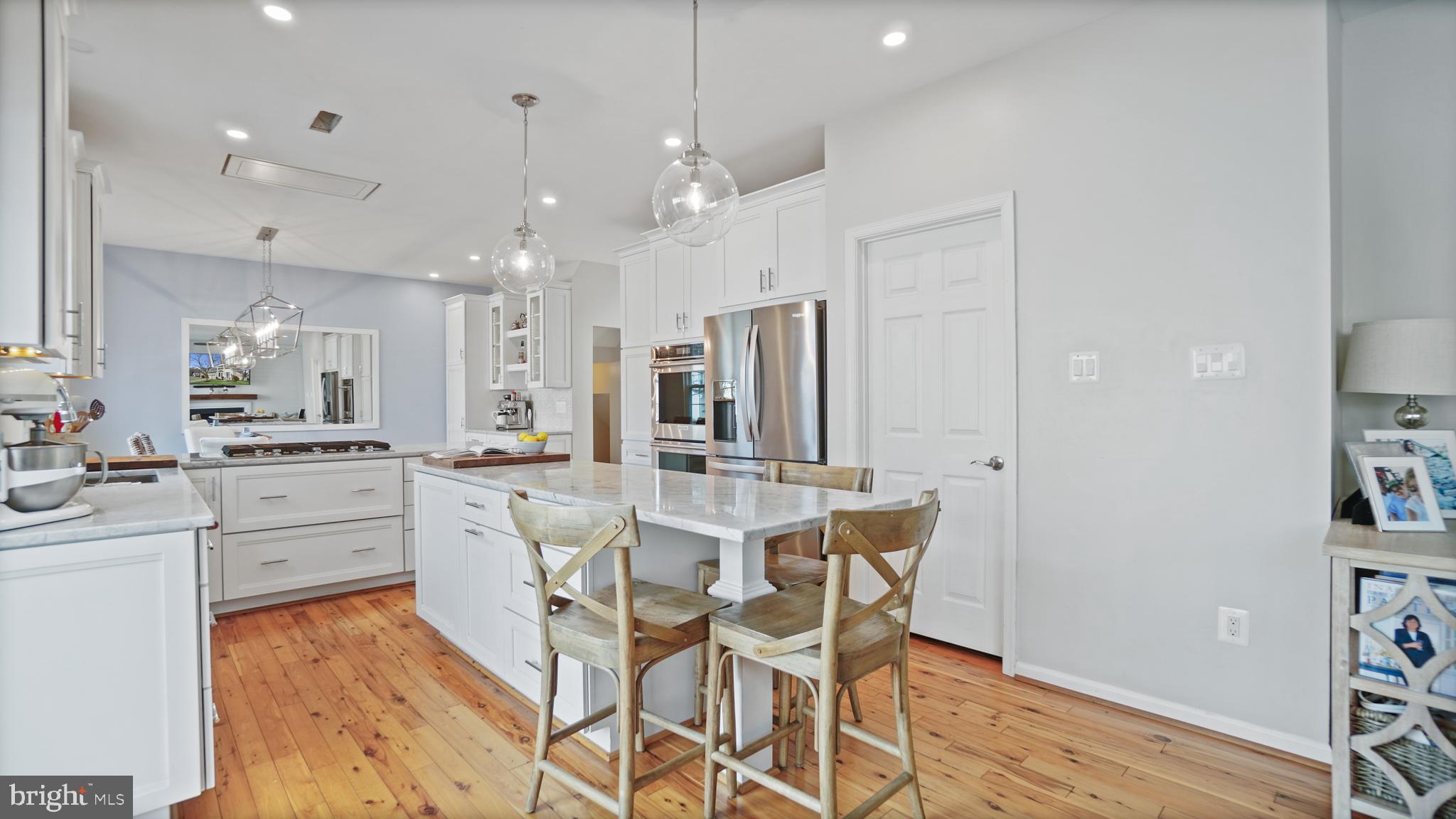 2801 Elsa Court Crofton, MD 21054 - Photo 17 of 58 a large white kitchen with cabinets a island a stove a dining table and chairs