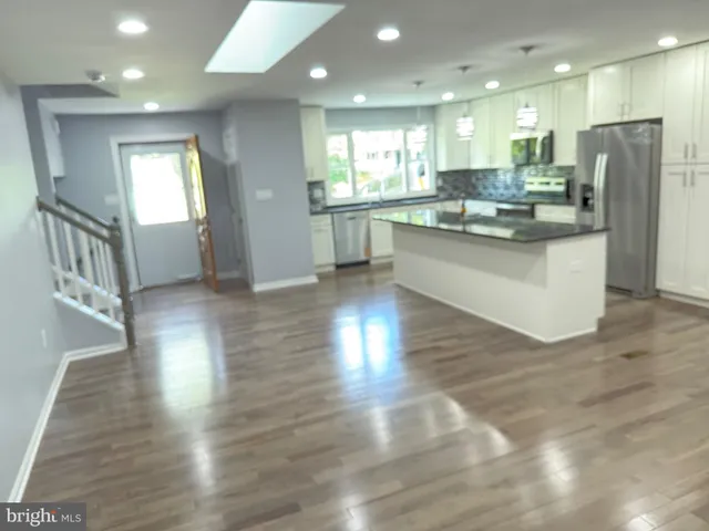 a kitchen with stainless steel appliances granite countertop a refrigerator a sink dishwasher and a stove with wooden floor