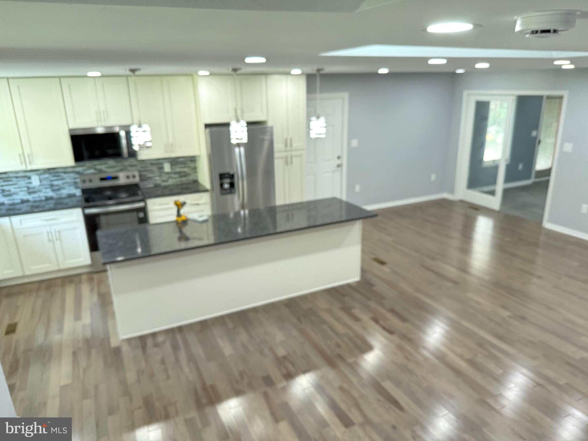 7810 Newington Woods Drive Springfield, VA 22153 - Photo 30 of 50 a large kitchen with stainless steel appliances a large counter top a stove and a wooden floors