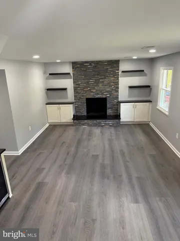 an empty room with wooden floor fireplace and windows