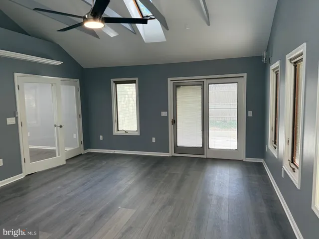 an empty room with wooden floor fan and windows