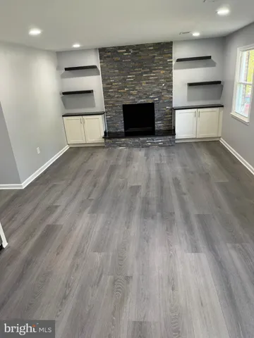 a view of kitchen and empty room with wooden floor fireplace