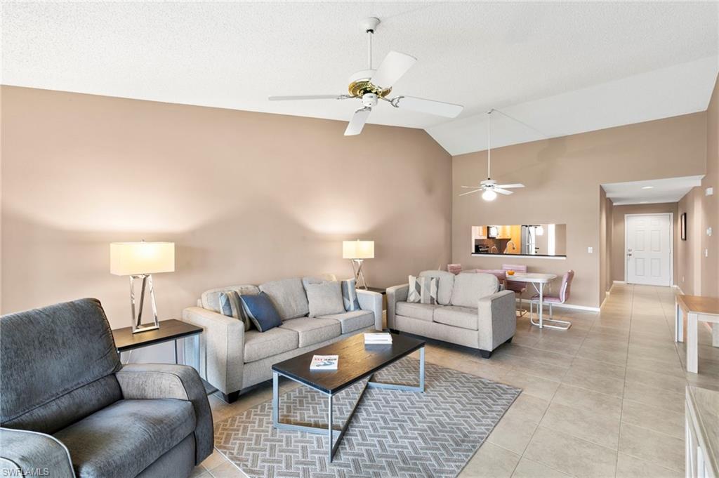 236 Pebble Beach Circle, Unit A202 Naples, FL 34113 - Photo 6 of 25 a living room with furniture a chandelier and a lamp