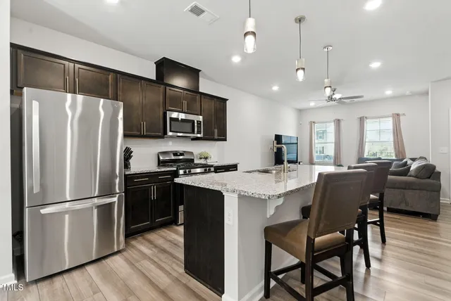 a living room with furniture kitchen view and a wooden floor
