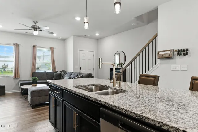 a kitchen with stainless steel appliances granite countertop a refrigerator a stove a sink a microwave oven with a dining table and chairs