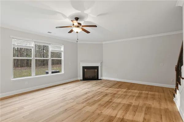 a view of an empty room with a window and wooden floor