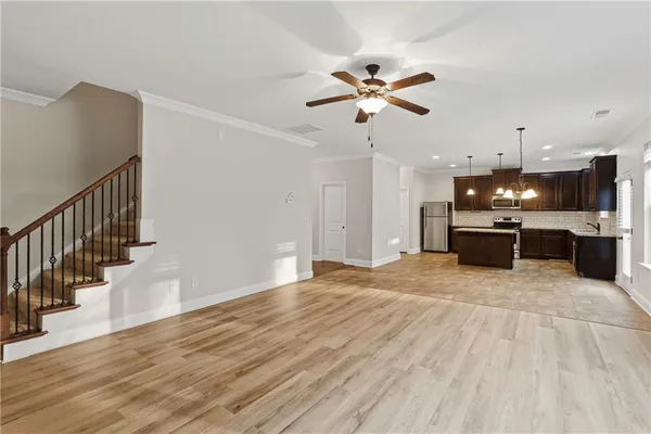 a view of an empty room with wooden floor and a kitchen