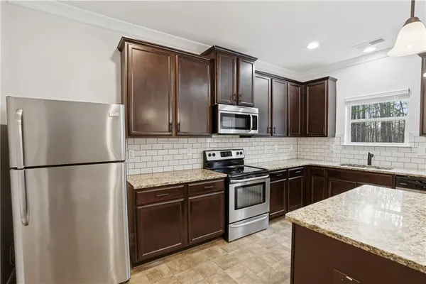a kitchen with granite countertop a refrigerator and a sink
