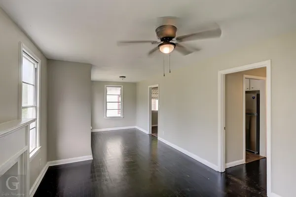 an empty room with wooden floor and windows