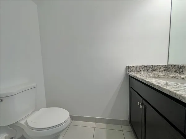 a bathroom with a granite countertop toilet and a sink