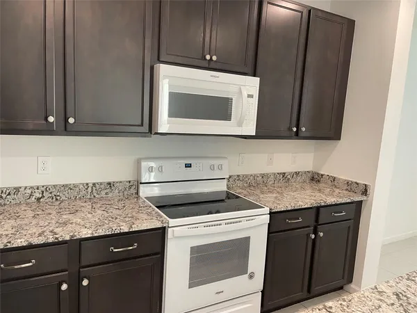 a kitchen with granite countertop wood cabinets and a stove top oven