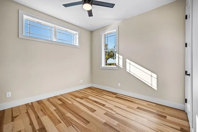 a view of a big room with wooden floor and windows