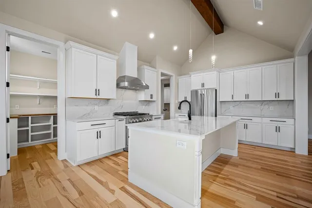 a large white kitchen with kitchen island a stove a sink a refrigerator and cabinets