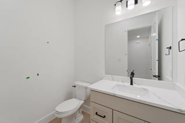 a bathroom with a granite countertop sink a toilet and a mirror