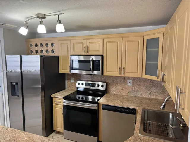 a kitchen with stainless steel appliances granite countertop a stove a refrigerator and a microwave