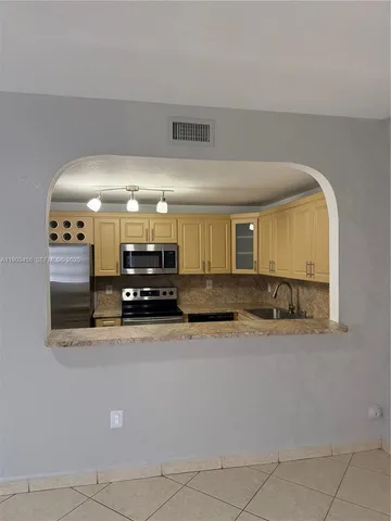 a kitchen with kitchen island a sink and a stove
