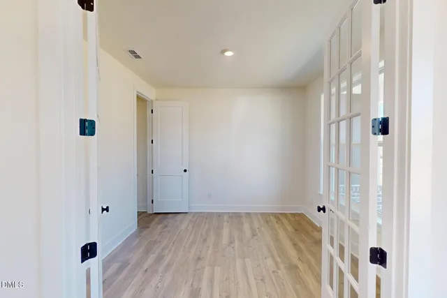 a view of a room with wooden floor a ceiling fan and a kitchen
