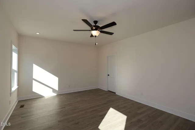 an empty room with a ceiling fan and windows