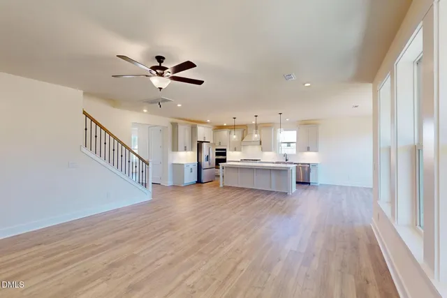 a view of an empty room with a kitchen and wooden floor